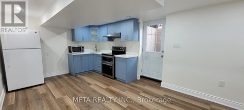 A kitchen with blue cabinets and a white refrigerator.