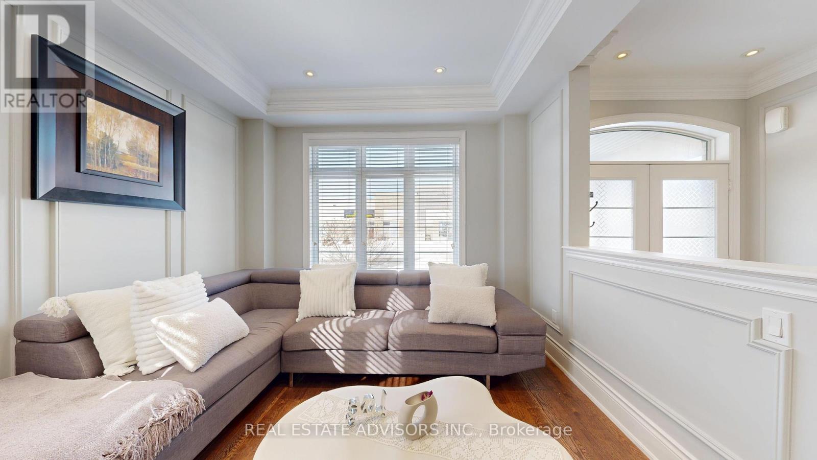 A living room with a grey couch and a painting on the wall.