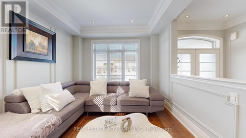 A living room with a grey couch and a painting on the wall.