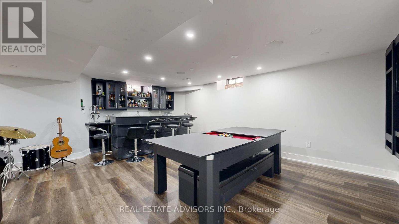 A room with a pool table and a bar area.
