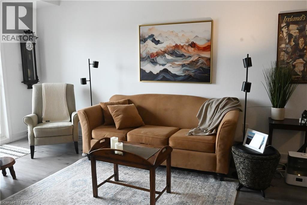A living room with a brown couch, a painting, and a chair.
