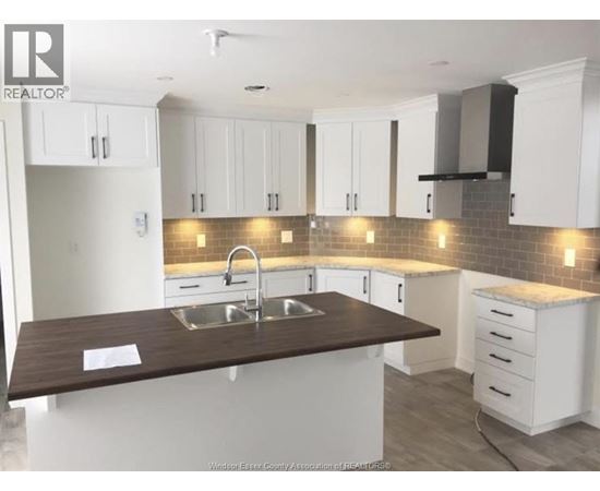 A kitchen with white cabinets and a brown countertop.