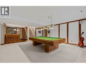 A pool table in a room with a guitar and a chair.