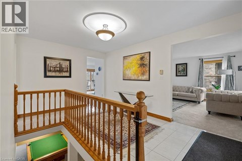A living room with a staircase and a painting on the wall.
