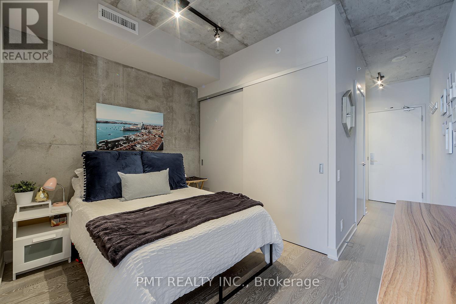 A bedroom with a bed, nightstand, and a painting on the wall.