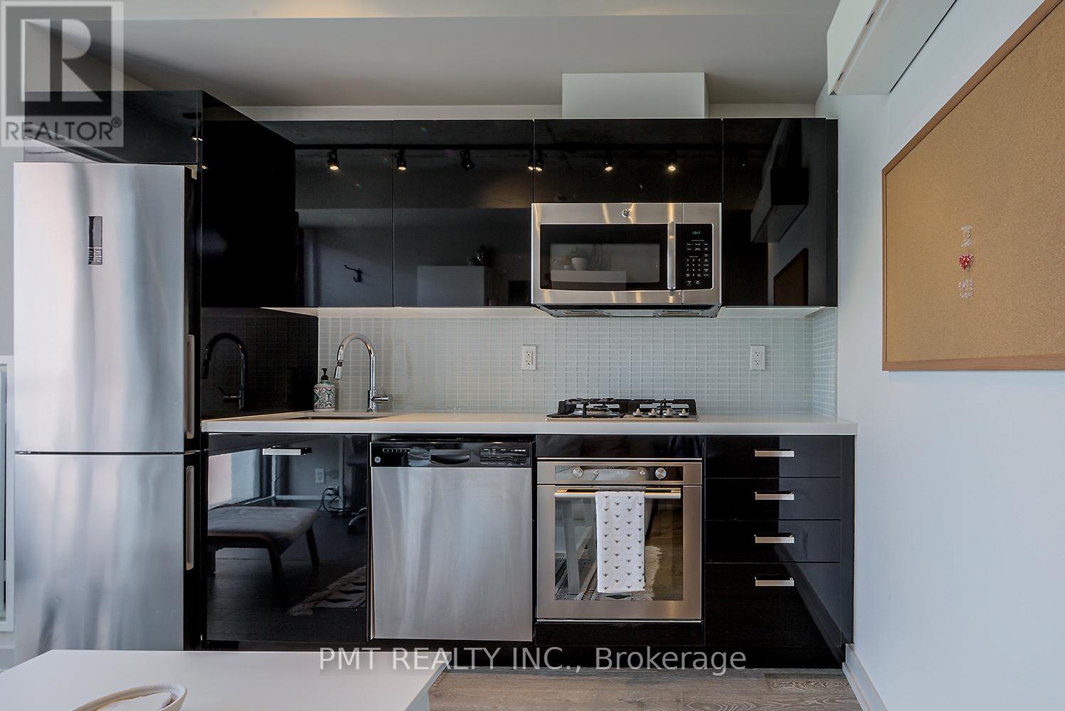 A modern kitchen with a stainless steel refrigerator and a microwave above the stove.
