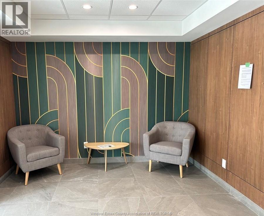 Two grey chairs and a table are in front of a green and gold wall.