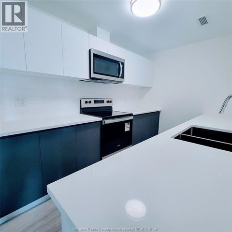 A kitchen with a microwave and oven mounted on the wall.