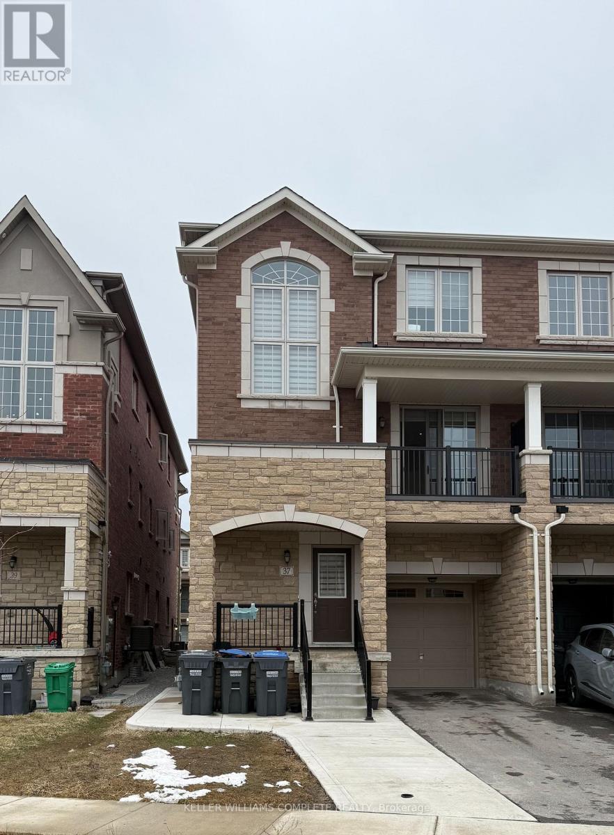 A brown brick house with a balcony is in front of a red brick house.