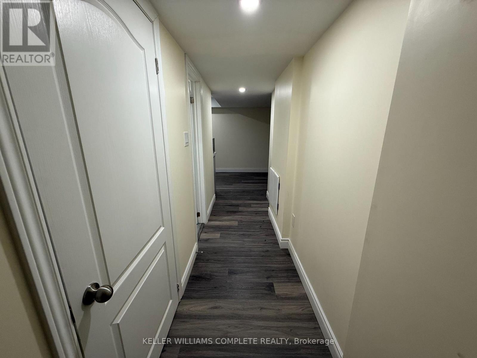 A hallway with a door on the left and a brokerage logo on the wall.