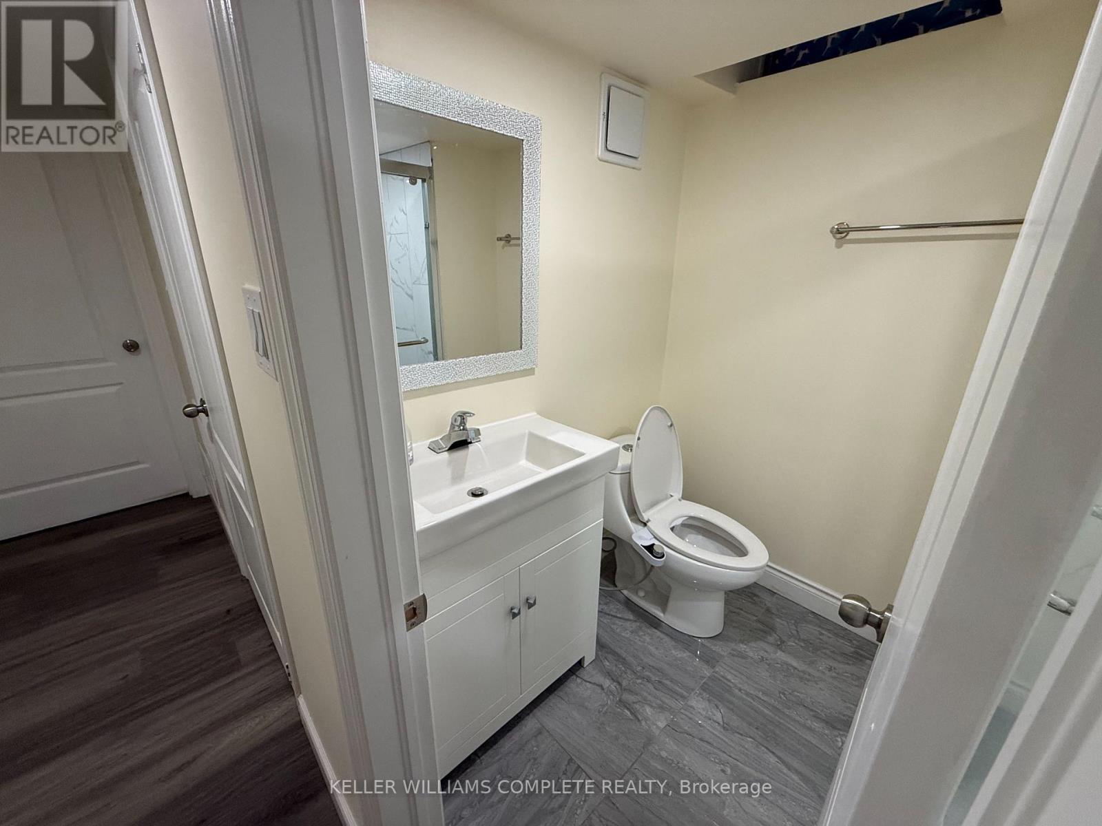 A bathroom with a toilet, sink, and mirror.