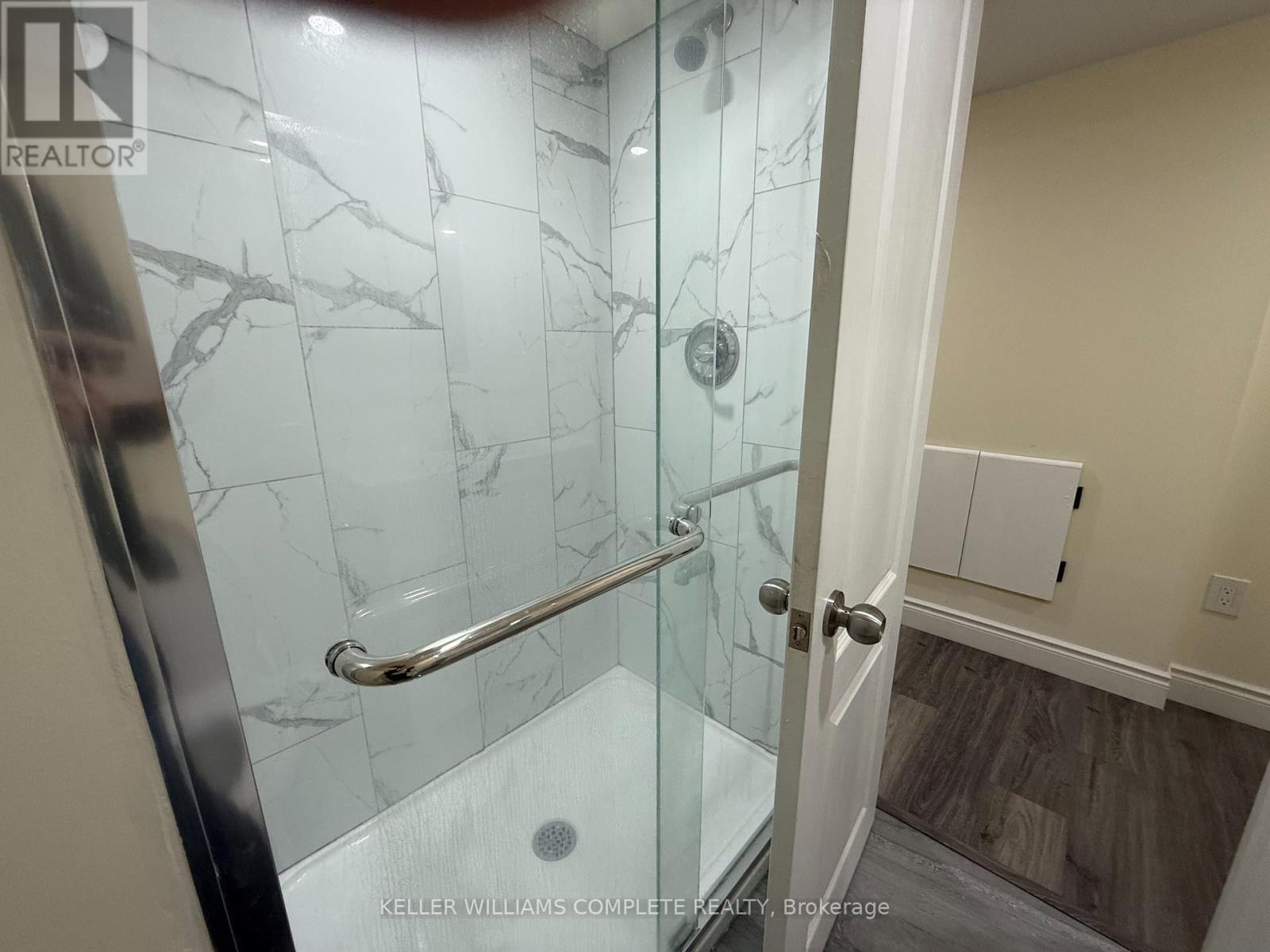 A glass shower door with a silver handle.