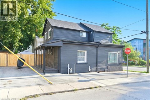 A grey house with a stop sign in front of it.