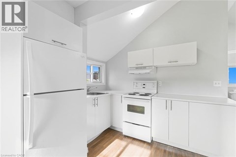 A white kitchen with a refrigerator, oven, and cabinets.