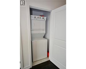 A white dishwasher and dryer are stacked in a small space.