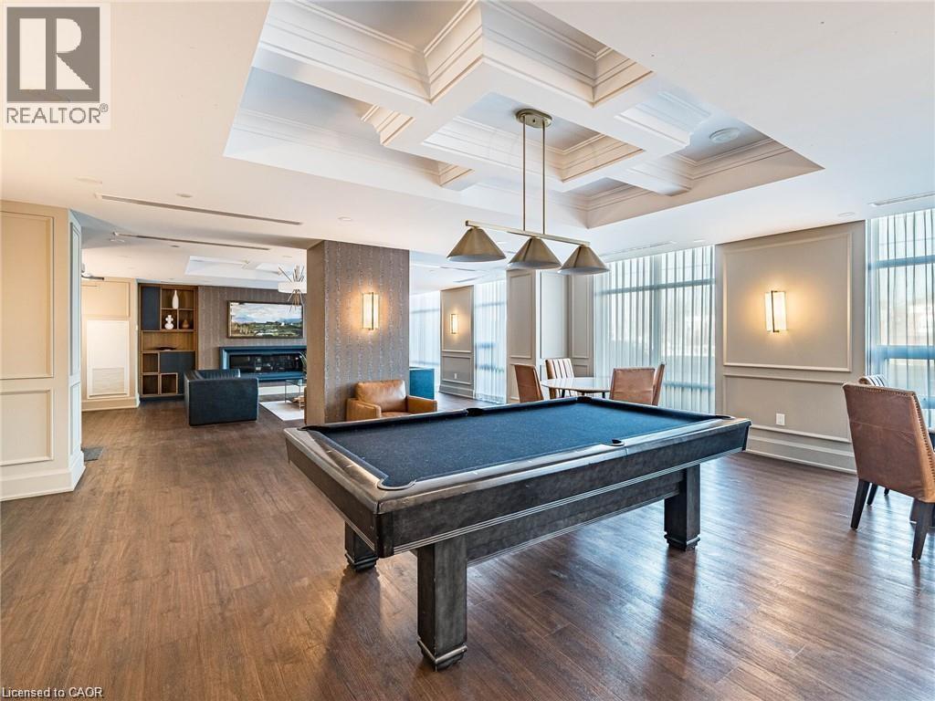 A pool table is in the middle of a room with wood floors and a high ceiling.