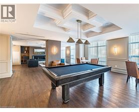 A pool table is in the middle of a room with wood floors and a high ceiling.
