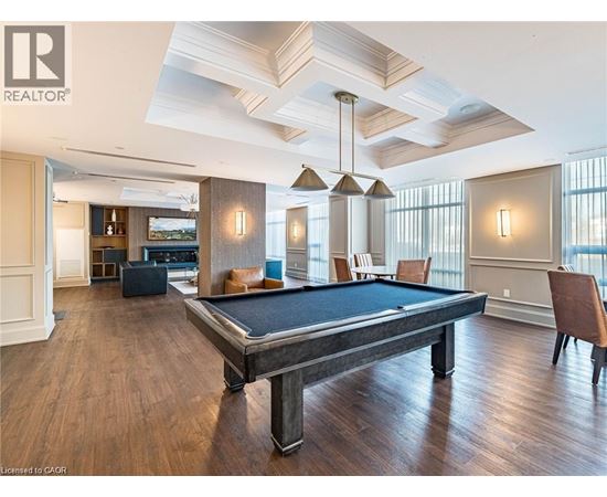 A pool table is in the middle of a room with wood floors and a high ceiling.