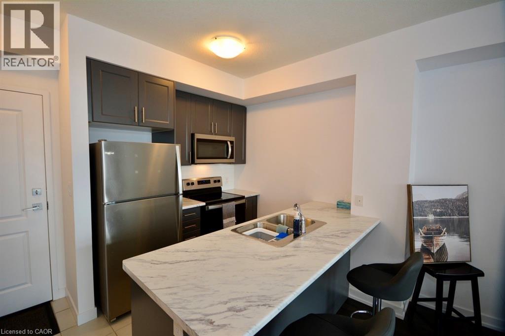 A kitchen with a refrigerator, microwave, and a counter with a sink.