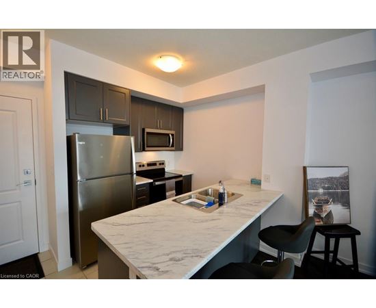 A kitchen with a refrigerator, microwave, and a counter with a sink.