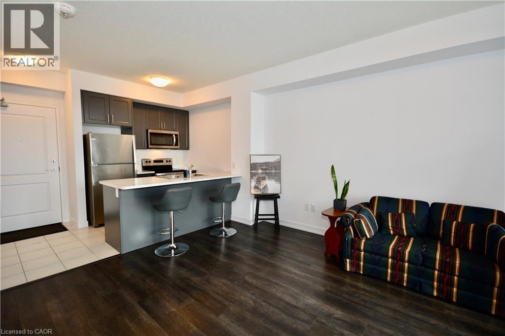 A living room with a striped couch and a kitchen area in the background.
