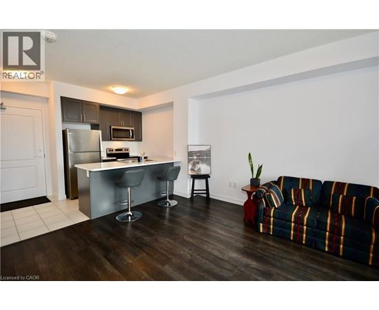 A living room with a striped couch and a kitchen area in the background.