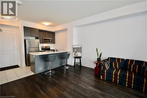 A living room with a striped couch and a kitchen area in the background.