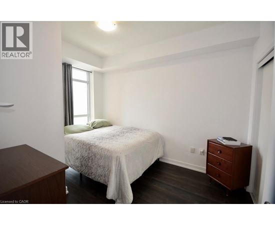 A bedroom with a bed, nightstand, and window.