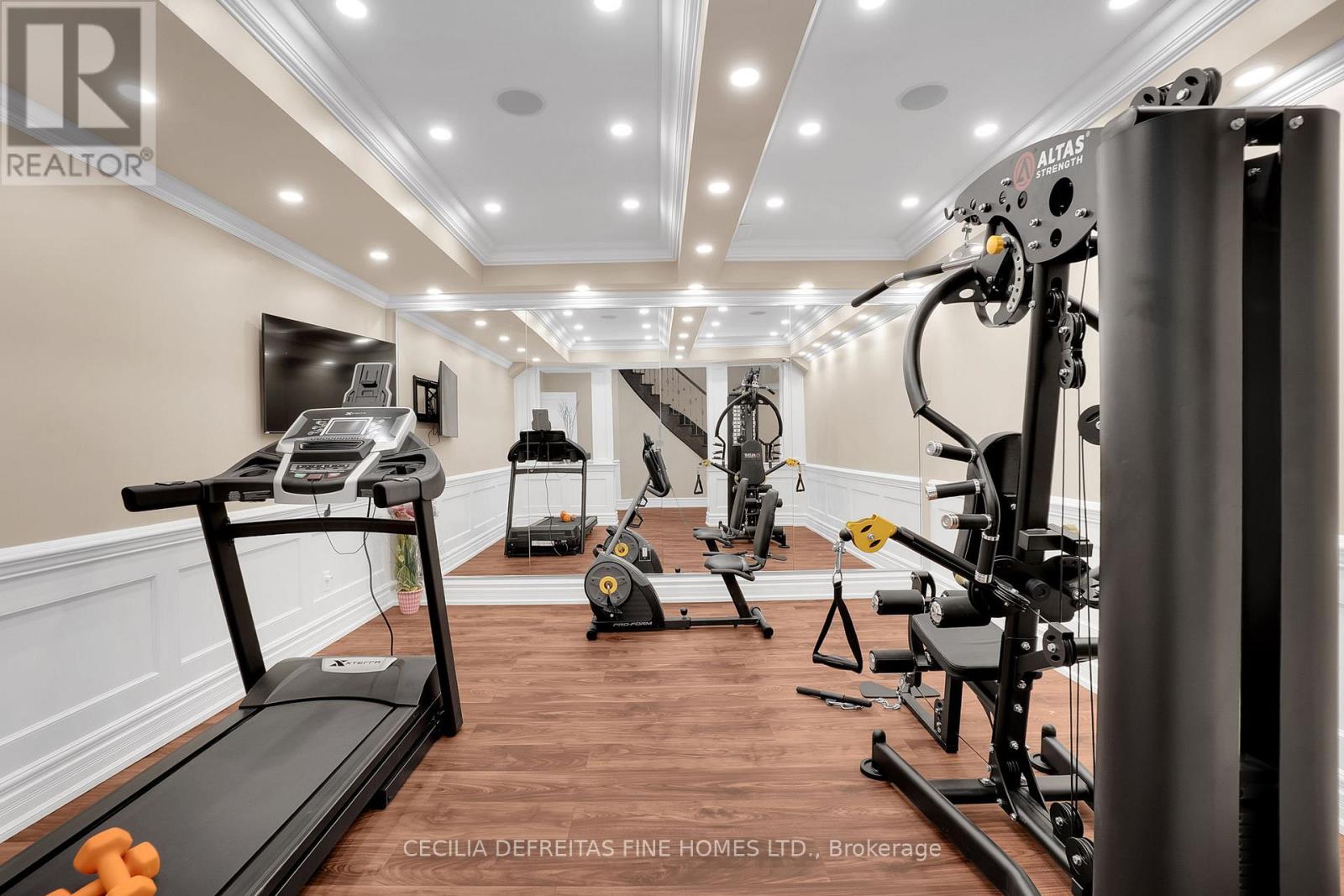 A well-lit home gym with a treadmill, exercise bike, and weight machine.