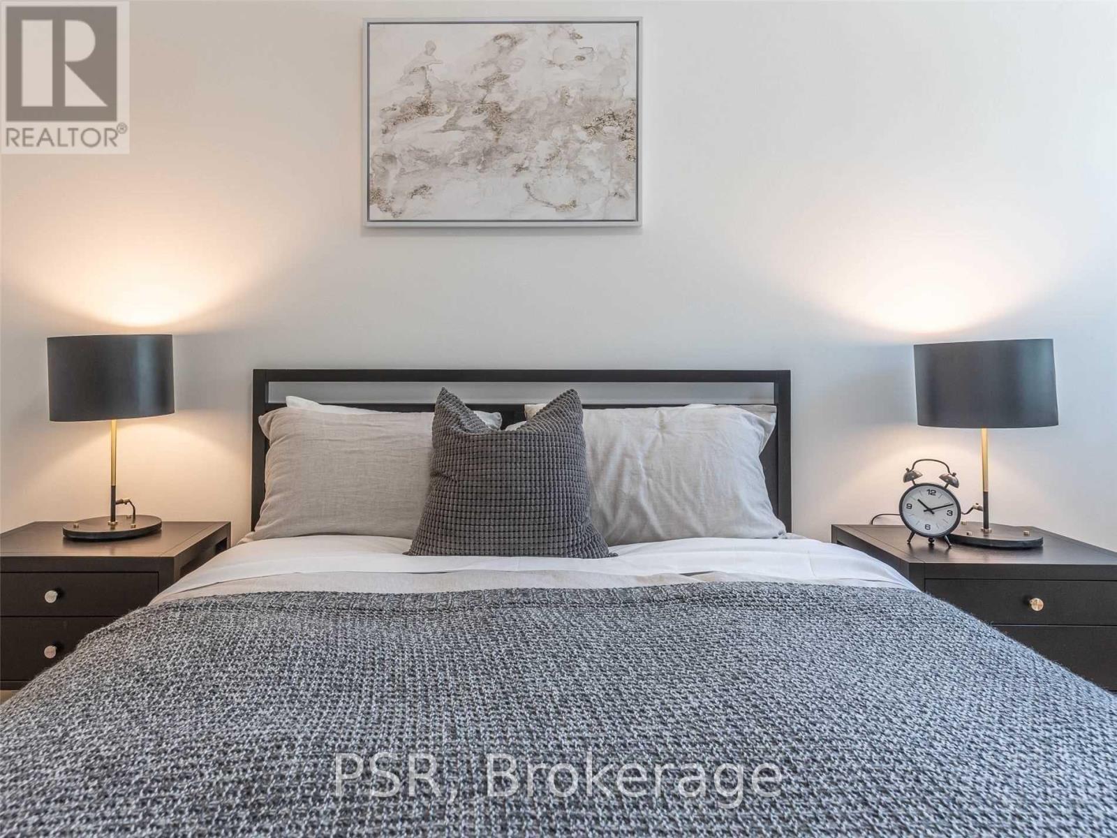 A bedroom with a bed, two nightstands with lamps, and a framed picture on the wall.