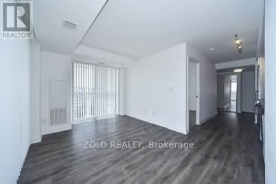 A spacious room with wooden flooring and white walls, labeled as Brokerage by Zolo Realty.