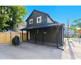 A two-story house with a garage door open and a black tarp on the ground.