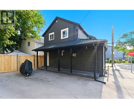 A two-story house with a garage door open and a black tarp on the ground.