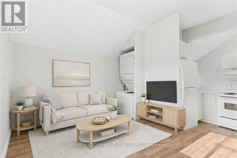 A living room with a white couch, a wooden coffee table, and a television on a wooden stand.