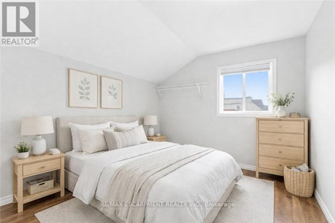A bedroom with a bed, nightstands, and a window.