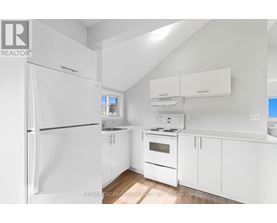 A white kitchen with a refrigerator, oven, and cabinets.