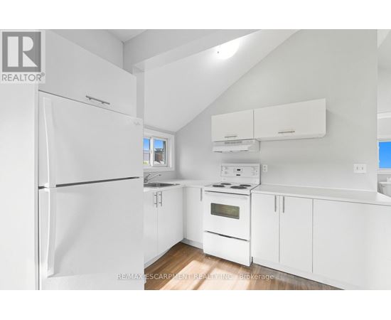 A white kitchen with a refrigerator, oven, and cabinets.