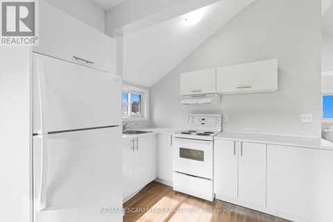 A white kitchen with a refrigerator, oven, and cabinets.
