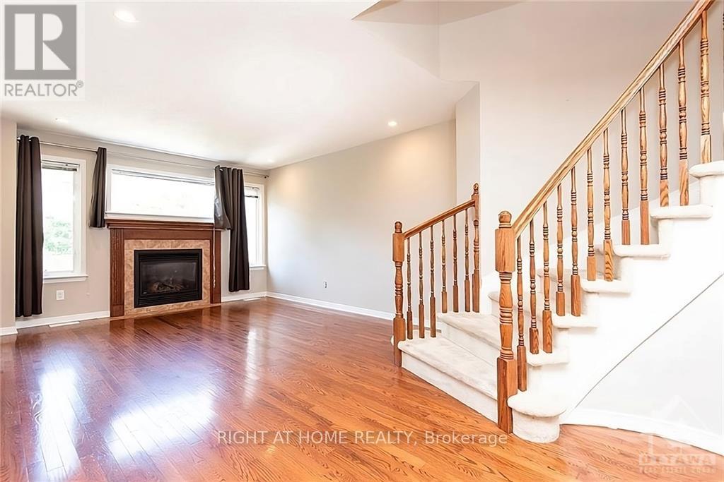 A spacious room with a fireplace and a staircase.