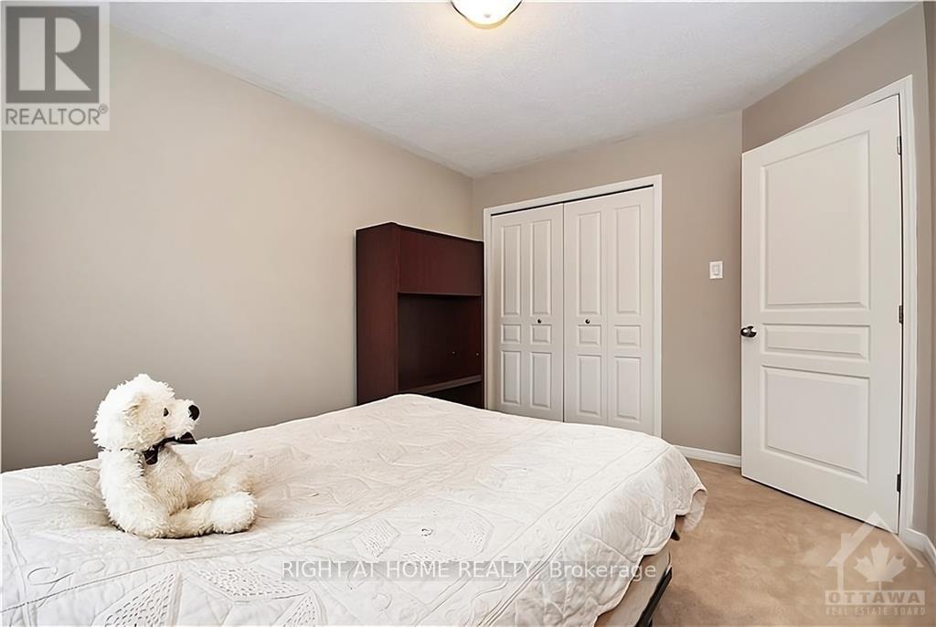 A white teddy bear is sitting on a bed in a bedroom.