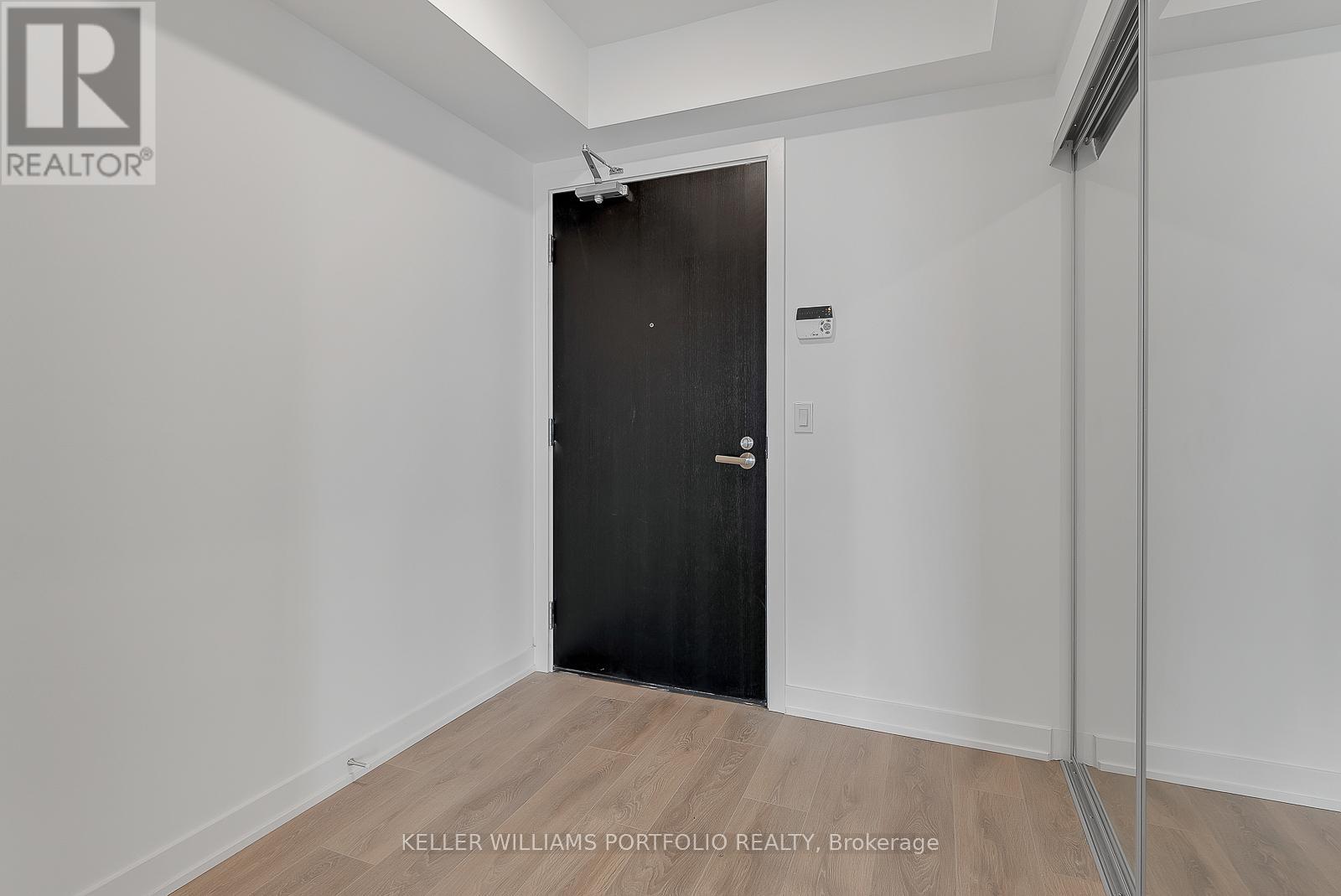 A black door in a white room with a wooden floor.