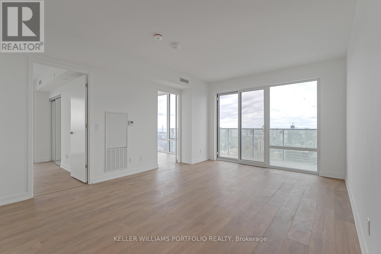 A spacious room with wooden floors and large windows overlooking the city.