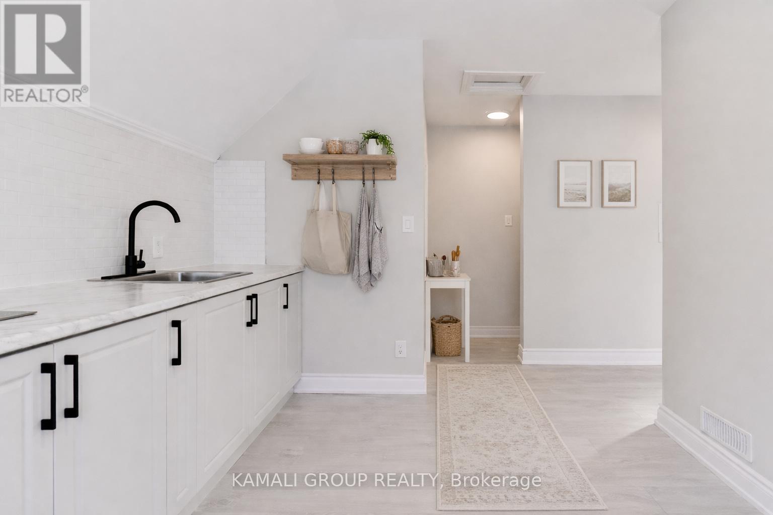A kitchen with white cabinets and a black faucet.
