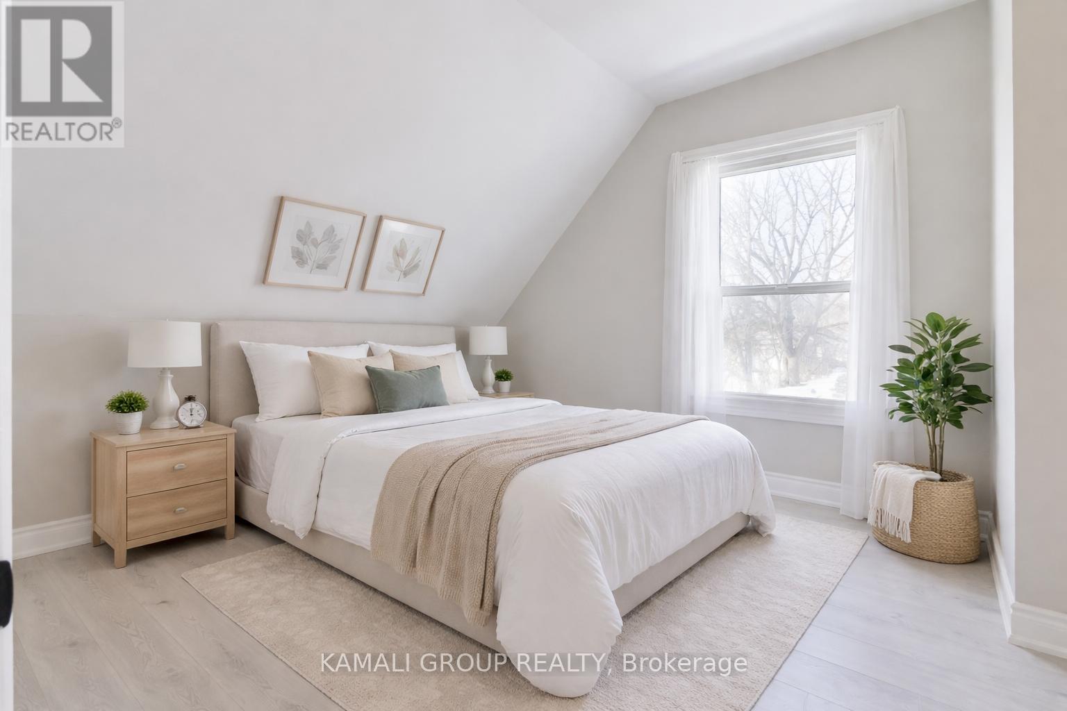 A bedroom with a bed, nightstand, and window.