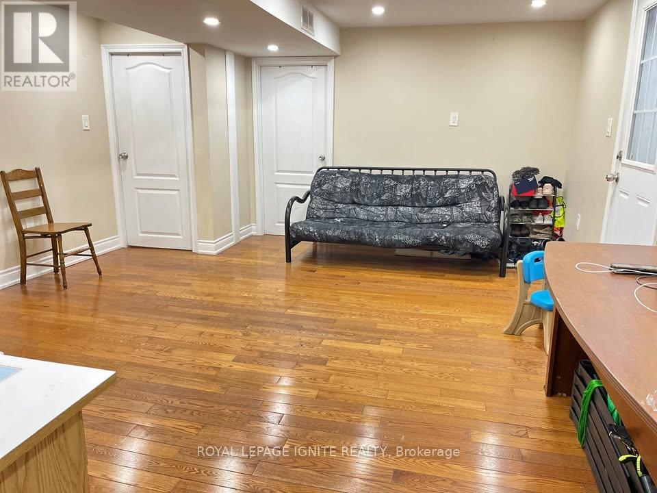 A living room with a black sofa and wooden floors.