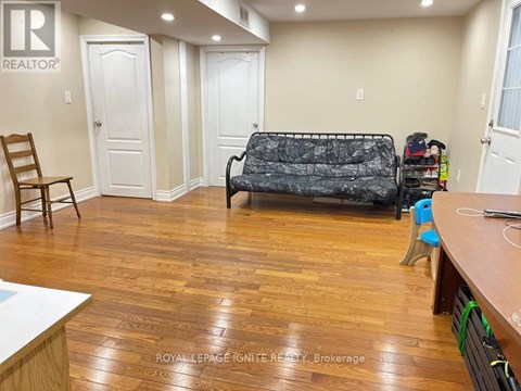 A living room with a black sofa and wooden floors.
