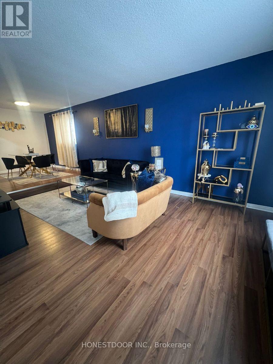 A living room with a black couch and a wooden floor.