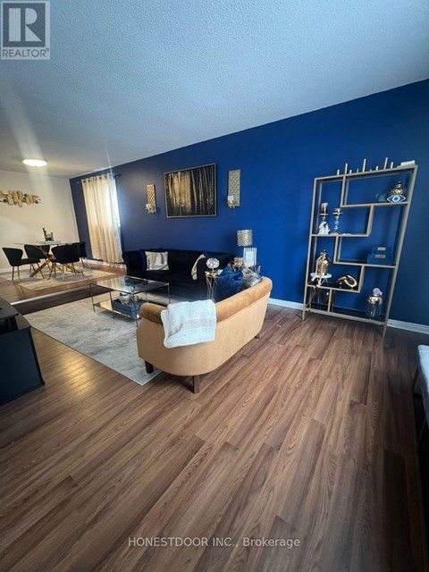A living room with a black couch and a wooden floor.