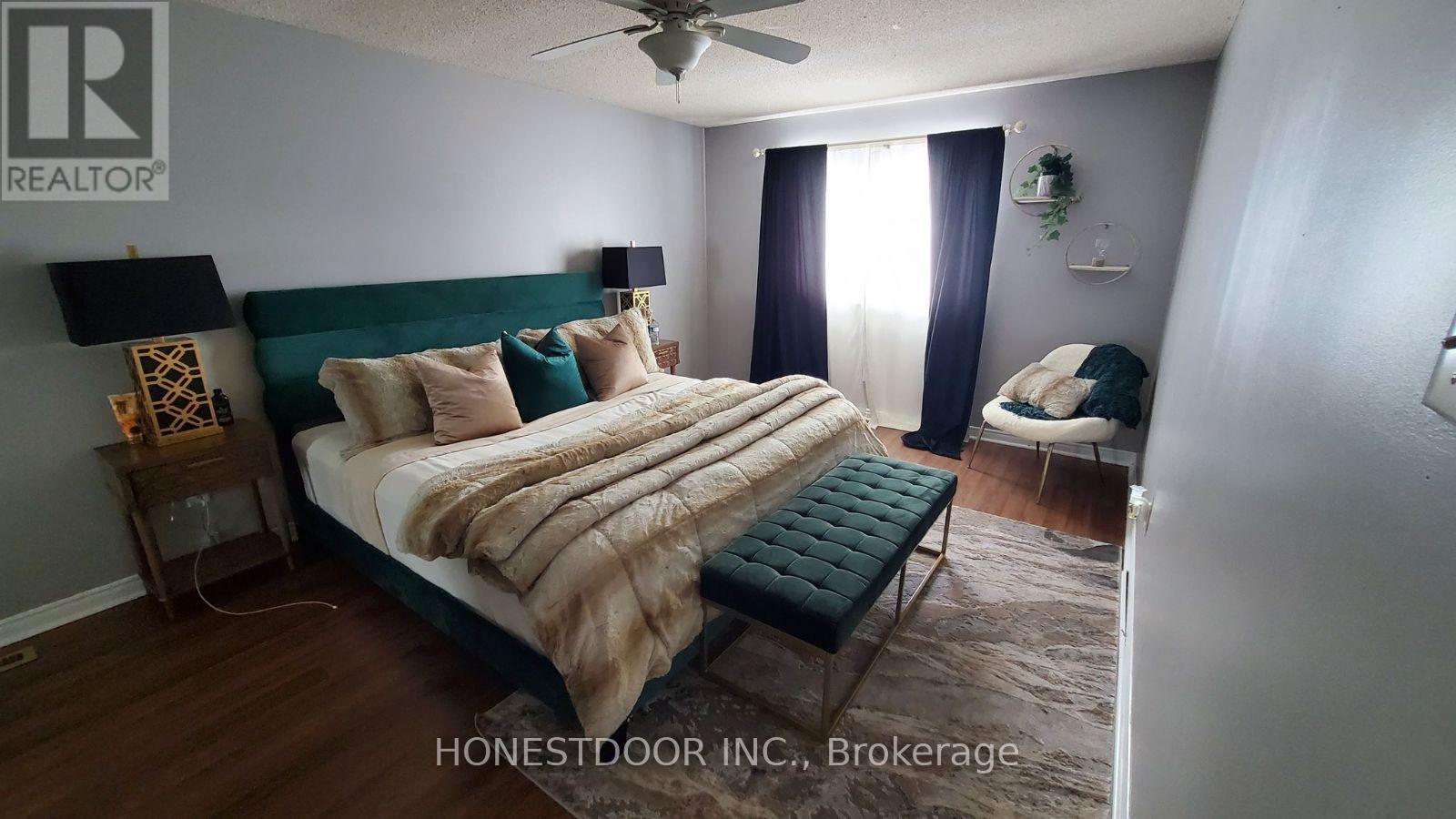 A bedroom with a bed, a chair, and a ceiling fan.