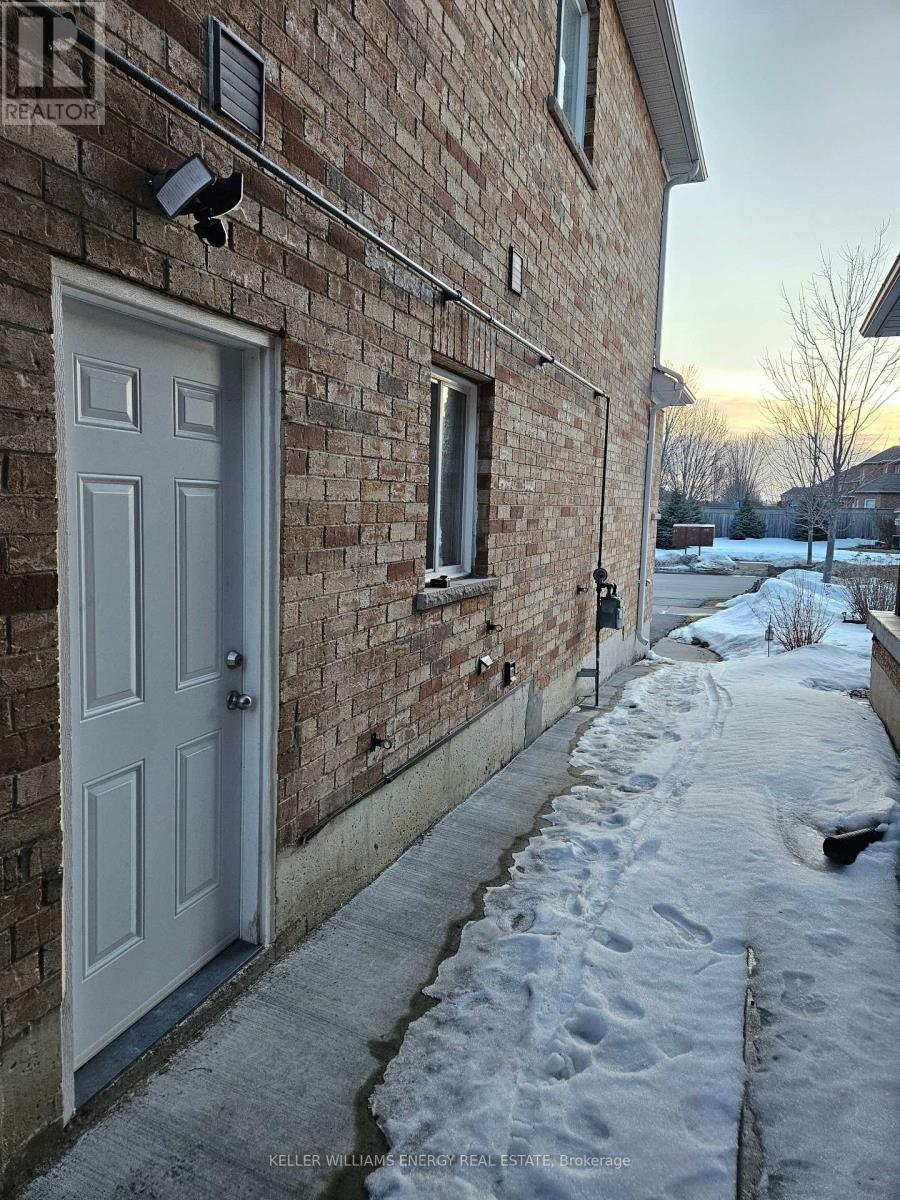 A snow-covered sidewalk leads to a white door on a brick building.